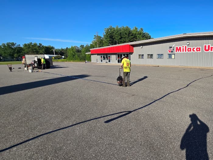 Hot rubber being used to seal cracks in parking lot.