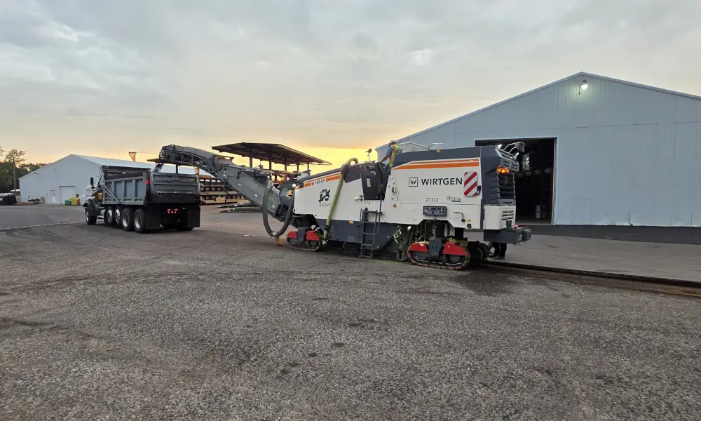 Asphalt milling machine removing old pavement and loading debris into a dump truck